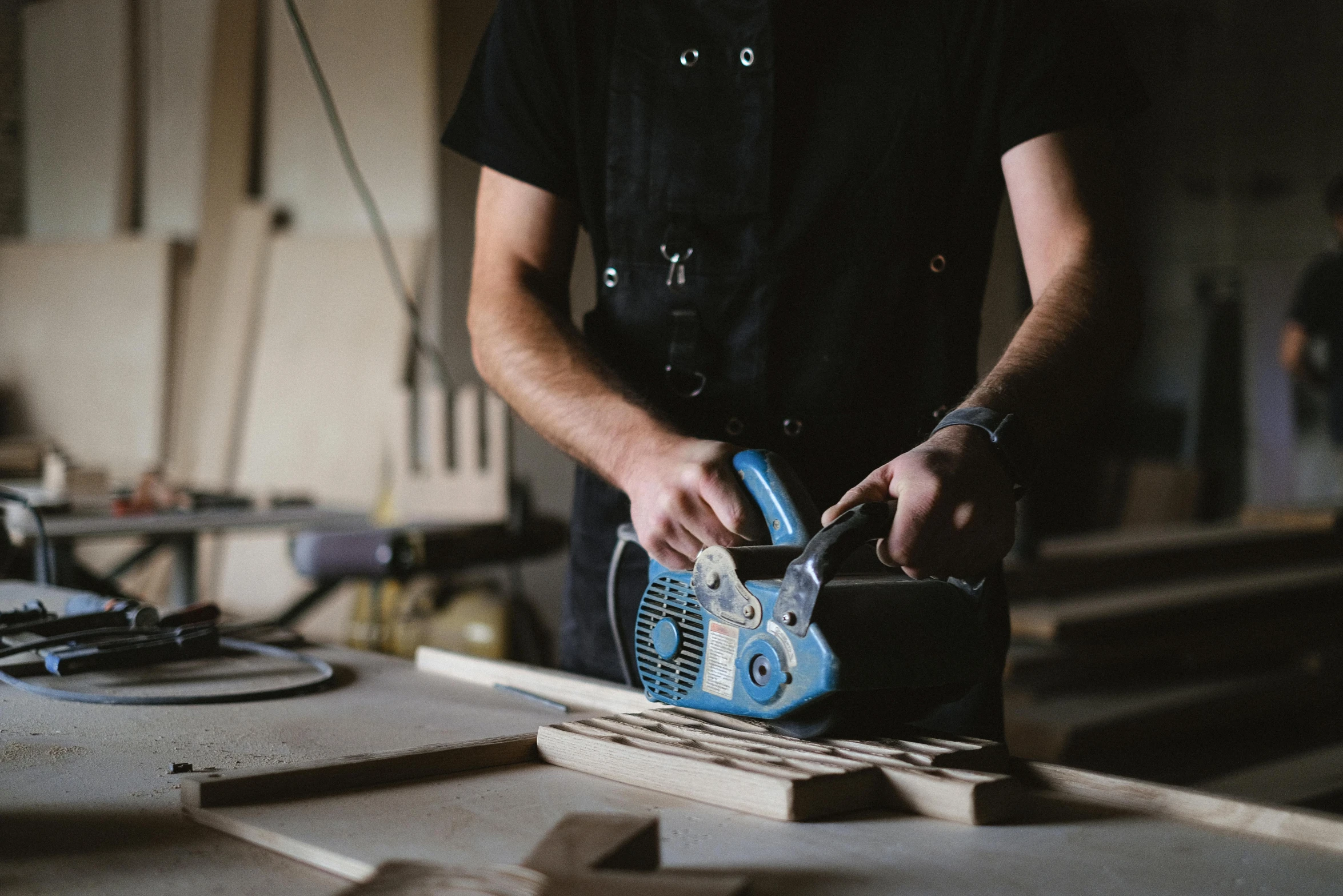 a man is working on a piece of wood, pexels contest winner, holding a chainsaw, blue print, lachlan bailey, album