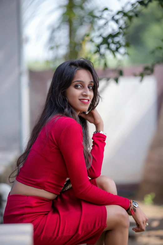 a woman in a red dress sitting on a bench, indian girl with brown skin, wearing a red outfit, profile image, while smiling for a photograph