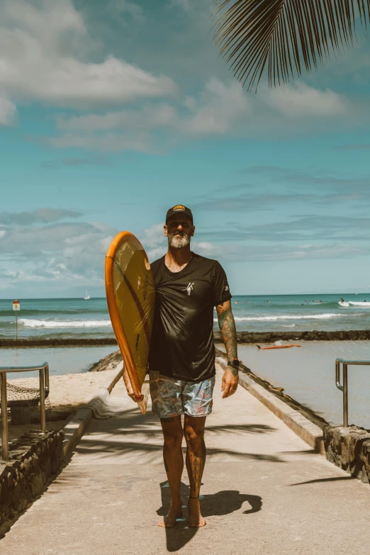 a man walking on a pier with a surfboard, posing for a picture, taken in 2 0 2 0, kauai, beard