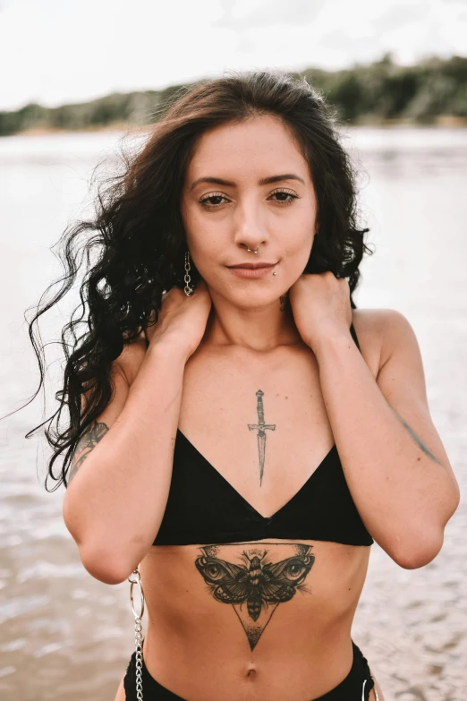 a woman standing on top of a beach next to a body of water, a tattoo, inspired by Mona Moore, trending on pexels, renaissance, posing together in bra, young woman with long dark hair, headshot, light skin