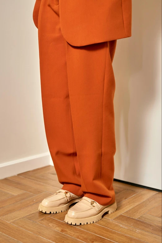 a man in an orange suit standing on a wooden floor, by Nina Hamnett, instagram, renaissance, baggy pants, color photograph, close - up photograph, taken in 2022