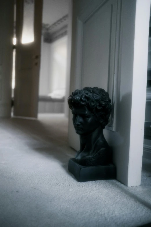 a black and white photo of a bust of a man, a statue, inspired by Sir Jacob Epstein, unsplash, apartment hallway, interior of a victorian house, soft light, resin statue