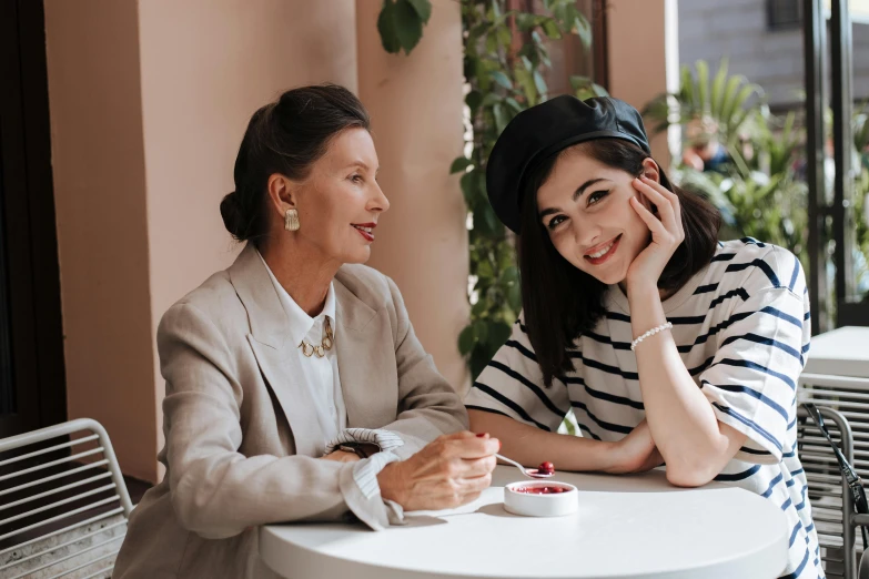 two women sitting at a table with a cup of coffee, a portrait, by Emma Andijewska, trending on pexels, wearing a french beret, with a kid, photoshoot for skincare brand, brunettes