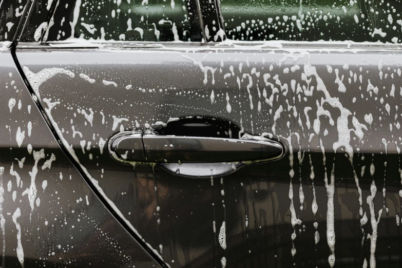 a close up of a car with a lot of water on it, a stipple, pexels contest winner, auto-destructive art, side view of a gaunt, dripping black and grey paint, 🦑 design, lots of bubbles