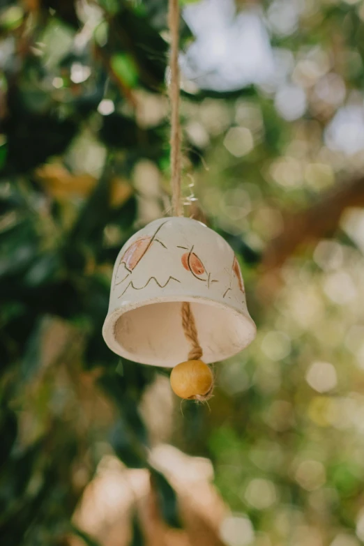 a bell hanging from the side of a tree, by Jessie Algie, unsplash, folk art, ceramic, square, lemon, eucalyptus