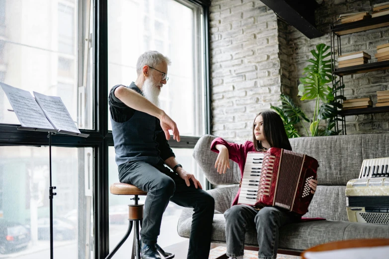 a man and a woman sitting on a couch playing an accordion, by Julia Pishtar, pexels contest winner, renaissance, old gigachad with grey beard, with a kid, sitting in a waiting room, next to window