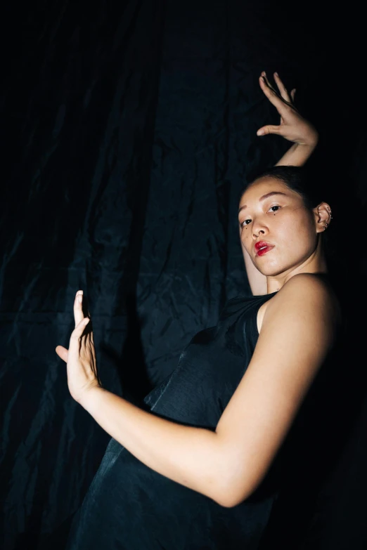 a woman in a black dress posing for a picture, an album cover, unsplash, queer woman, nanae kawahara, gestures, nights