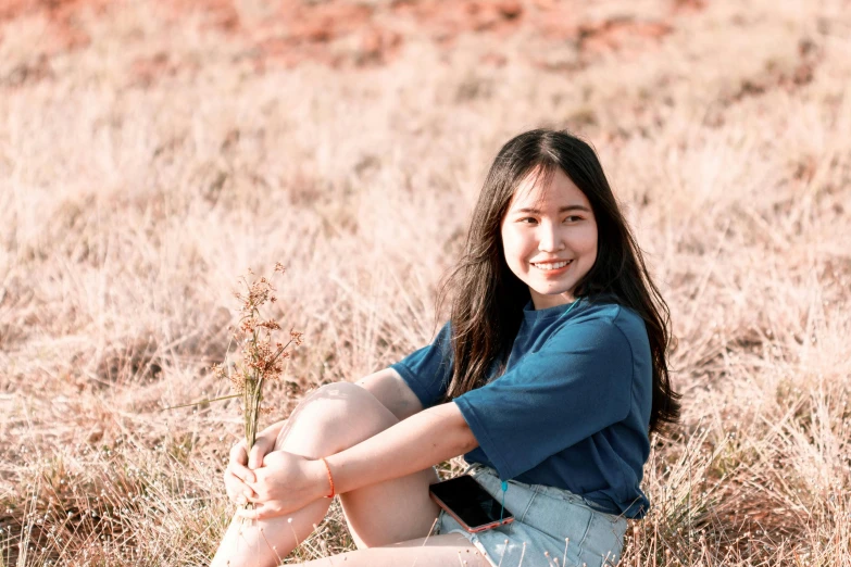 a woman sitting in the middle of a field, pexels contest winner, realism, young cute wan asian face, 1 6 years old, straya, smiling