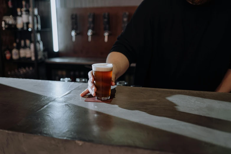 a person sitting at a bar with a glass of beer, aussie baristas, back of hand on the table, profile image, uncropped