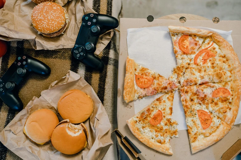 a pizza sitting on top of a table next to a game controller, by Julia Pishtar, pexels contest winner, eating burgers, flat lay, :14 flcl + jet grind radio, with bread in the slots
