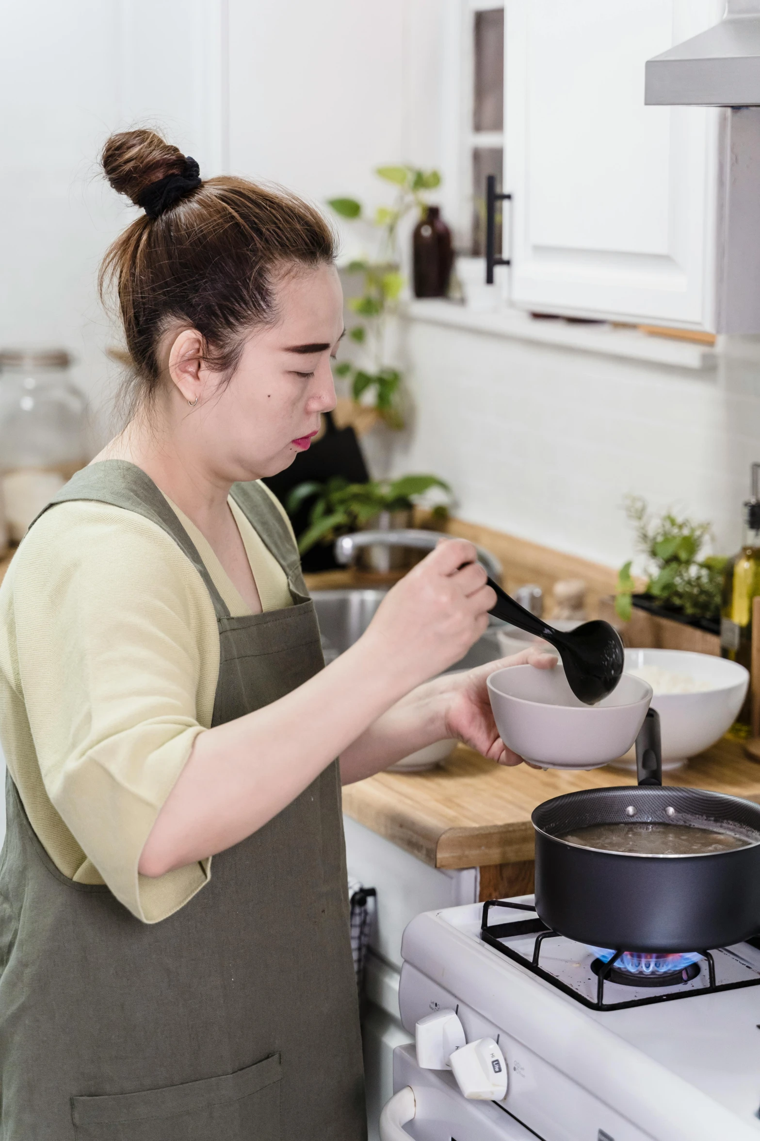 a woman in a kitchen preparing food on a stove, inspired by Ruth Jên, pexels contest winner, dau-al-set, brown gravy, square, japanese collection product, black
