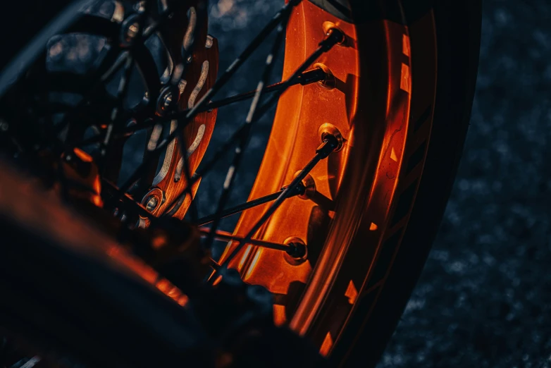 a close up of the front wheel of a motorcycle, pexels contest winner, hurufiyya, orange glow, dark-toned product photos, stacked image, back light