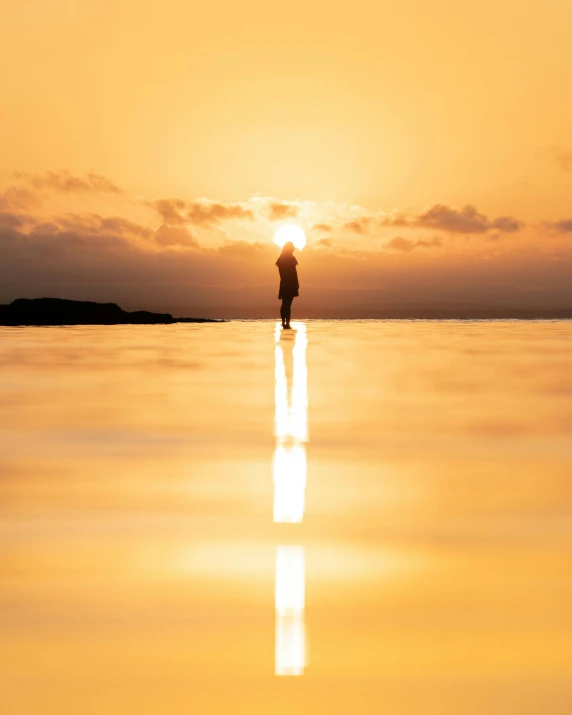 a person standing in the middle of a body of water at sunset, refracting light, trending photo