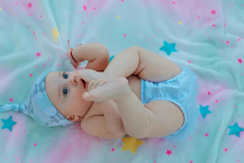 a baby in a diaper laying on a blanket, by Julia Pishtar, pexels contest winner, sky blue, tiny stars, cotton candy, handsome