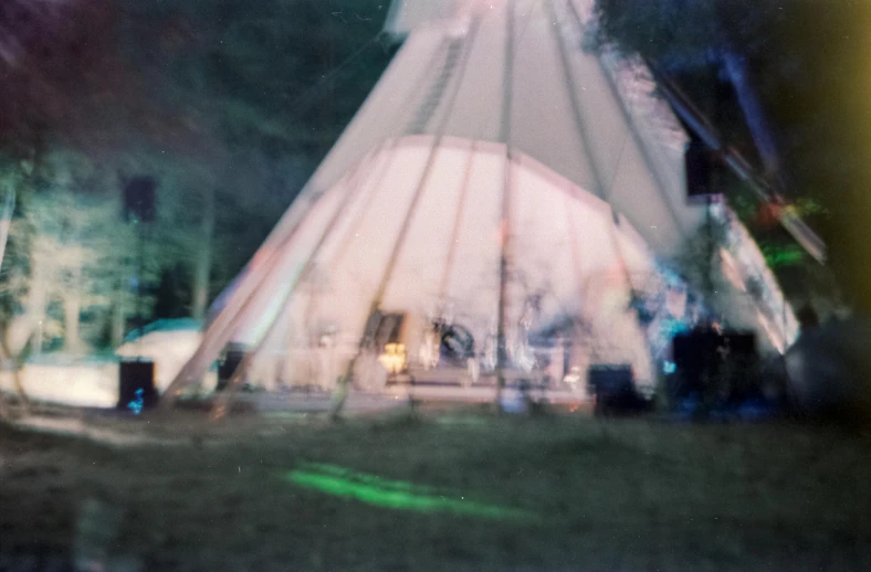 a group of people standing in front of a tent, a polaroid photo, by Emma Andijewska, pexels contest winner, temporary art, psychedelic organic shaman, teepee, frayed edges. light leaks, pavilion