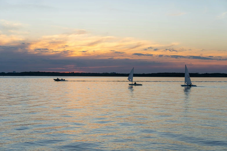 a group of sailboats floating on top of a body of water, in the evening, from wheaton illinois, fan favorite, sports photo