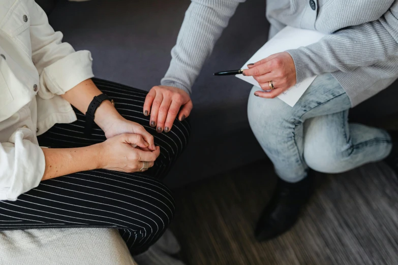 a couple of women sitting on top of a couch, trending on pexels, acupuncture treatment, giving an interview, hand on table, casually dressed