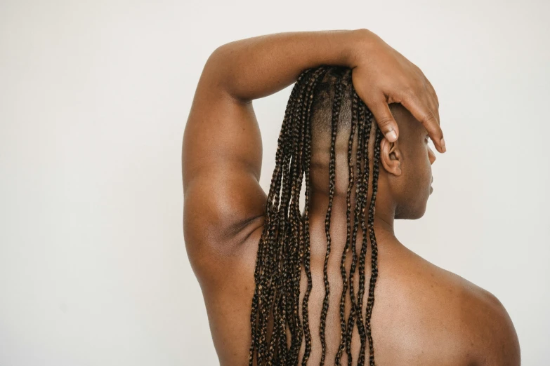 a close up of a person with long hair, by Olivia Peguero, trending on pexels, afrofuturism, flexing large muscles, woman with braided brown hair, arched back, raising an arm