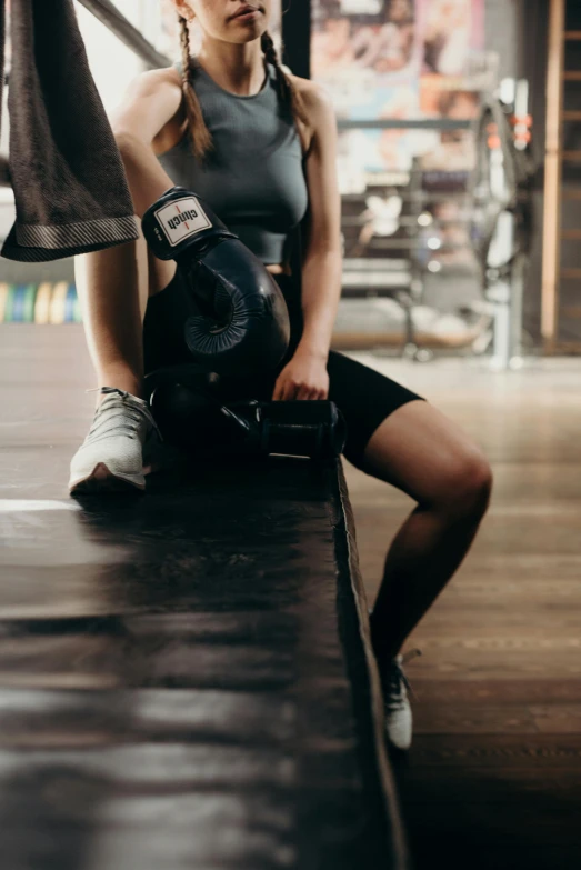 a woman sitting on a bench in a gym, pexels contest winner, boxing gloves, hip and leg shot, manuka, instagram picture