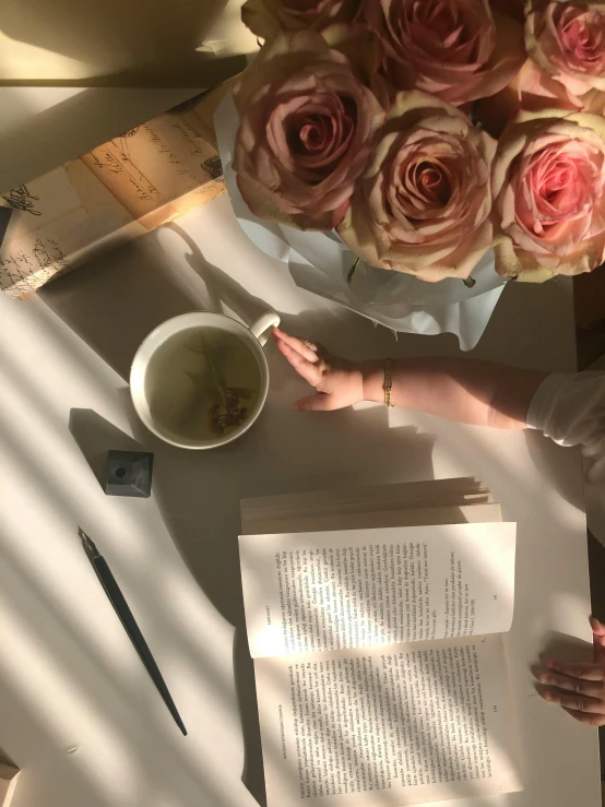 a woman sitting at a table with a cup of coffee, by Maggie Hamilton, trending on unsplash, romanticism, books and flowers, low quality photo, shot with iphone 1 0, melanchonic rose soft light