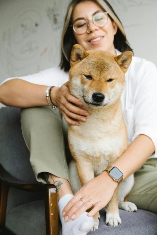 a woman sitting in a chair holding a dog, inspired by Shiba Kōkan, trending on unsplash, sōsaku hanga, wears a watch, square, 0, asian male