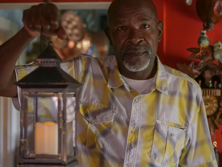 a man in a yellow and white shirt holding a lantern, tv show still, huell babineaux, cabin lights, romantic lead