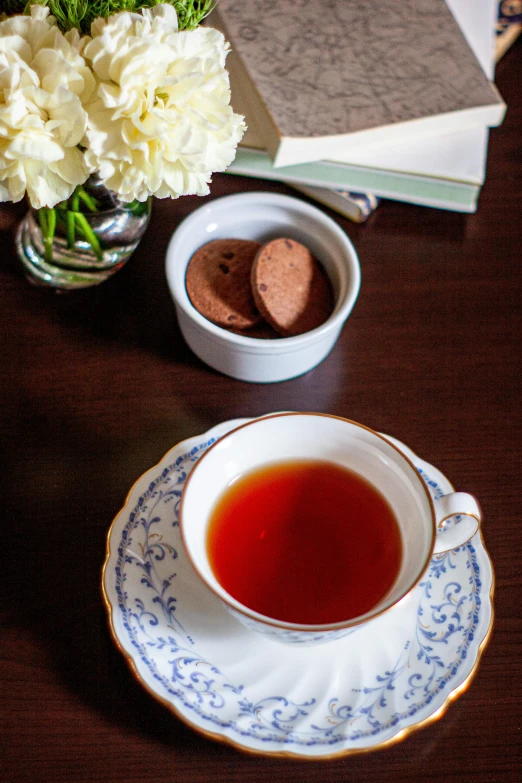 a cup of tea sitting on top of a wooden table, inspired by Richmond Barthé, chocolate, superior, blue, flowers