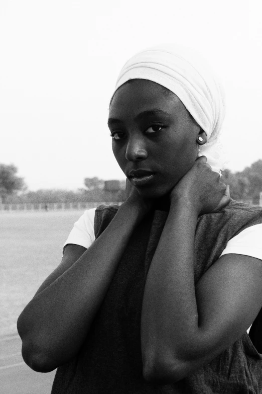 a black and white photo of a woman in a turban, inspired by Ras Akyem, on a soccer field, black teenage girl, kano), adut akech