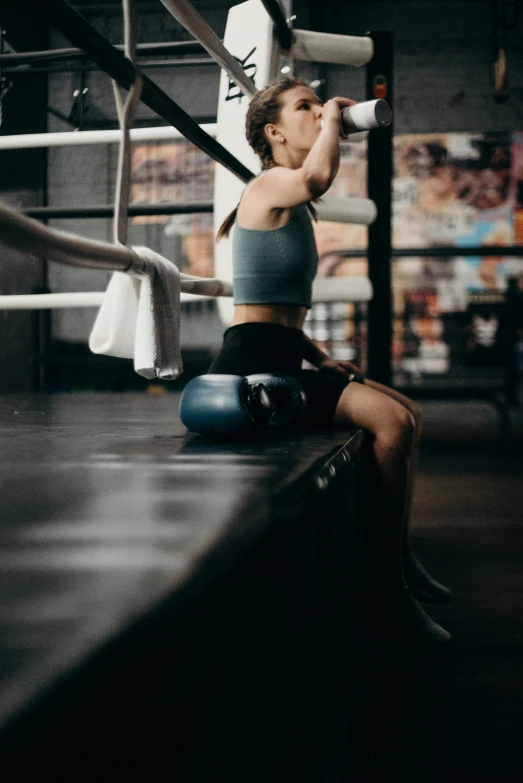 a woman sitting on the edge of a boxing ring, pexels contest winner, athletic crossfit build, lower back, hypersphere, low quality photo