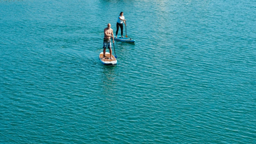 a couple of people riding paddle boards on top of a body of water, manly, brown and cyan blue color scheme, thumbnail, high angle shot