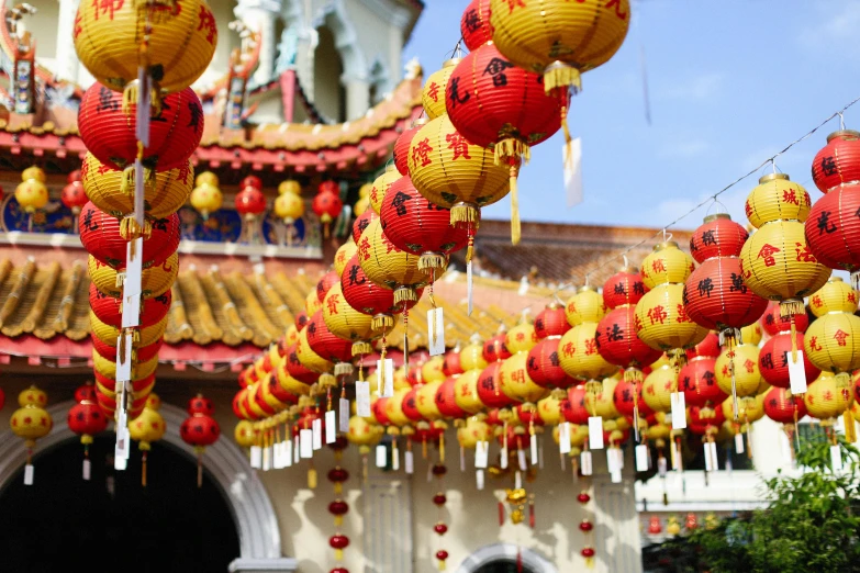 a bunch of red and yellow lanterns hanging from the ceiling, inspired by Ju Lian, pexels, in front of a temple, 🦩🪐🐞👩🏻🦳, square, ross tan