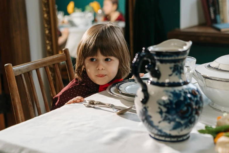 a little boy that is sitting at a table, by Adam Marczyński, pexels contest winner, arts and crafts movement, fine china, looking confident, dinner is served, avatar image