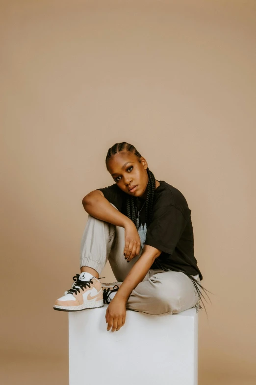 a woman sitting on top of a white box, an album cover, by Dulah Marie Evans, trending on pexels, sneakers, portrait androgynous girl, light-brown skin, confident stance