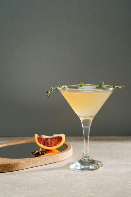 a cocktail sitting on top of a table next to a cutting board, inspired by Ndoc Martini, renaissance, ivy's, on grey background, savory, abcdefghijklmnopqrstuvwxyz