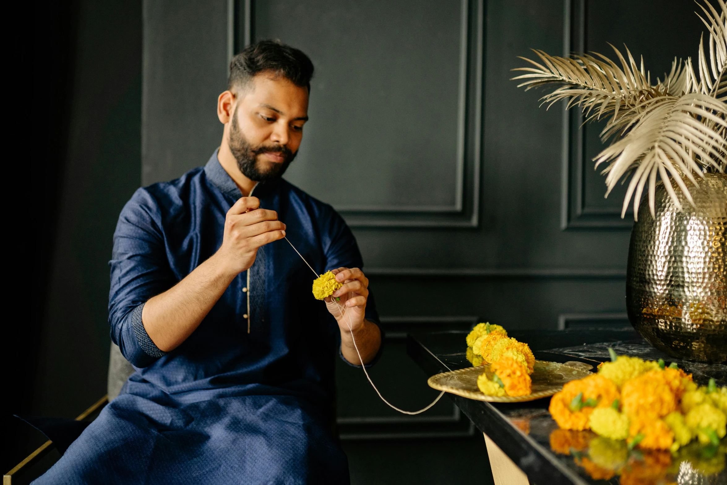 a man sitting at a table with a plate of food, a still life, trending on unsplash, hurufiyya, wearing a silk kurta, picking up a flower, gold and indigo, avatar image