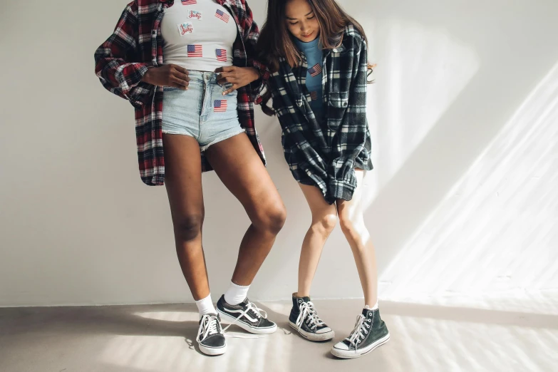 a couple of women standing next to each other, trending on pexels, wearing shorts, black teenage girl, on a checkered floor, wearing ragged clothing