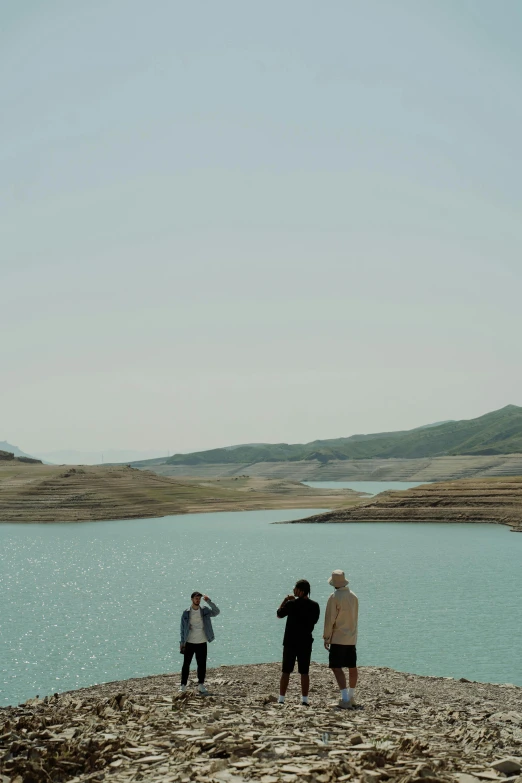 a group of people standing next to a body of water, by Elsa Bleda, hurufiyya, hills, hot day, vfx shot, water reservoir