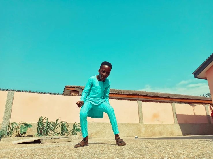 a man sitting on a skateboard in front of a building, an album cover, pexels contest winner, happening, teal suit, in africa, 14 yo berber boy, dynamic dancing pose