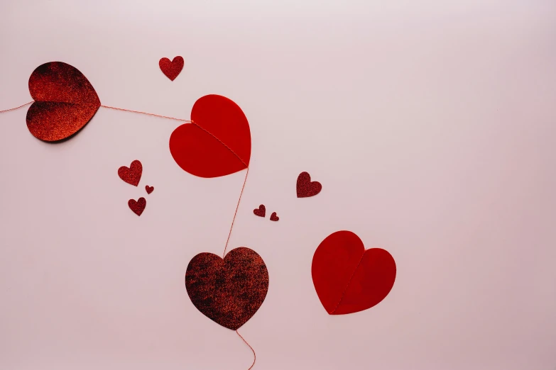 a bunch of red hearts hanging from a string, by Valentine Hugo, pexels, on a pale background, profile image, foil, shot on sony a 7