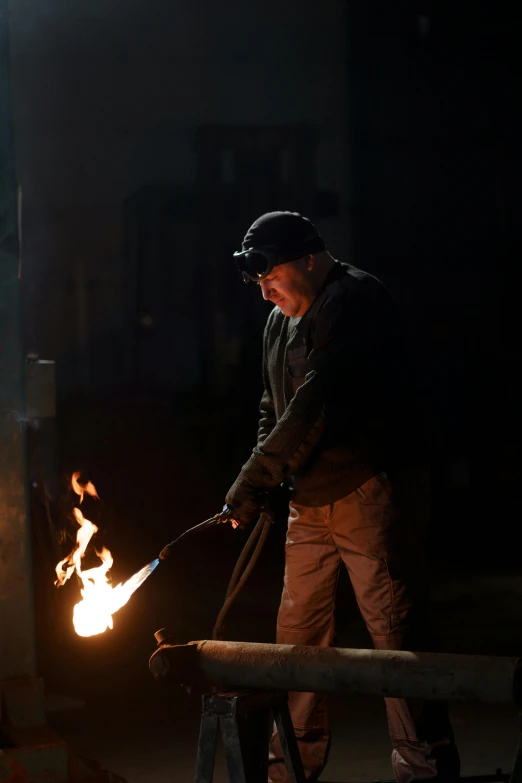 a man that is standing in front of a fire, industrial lighting, wielding a wrench, cast iron material, ignant