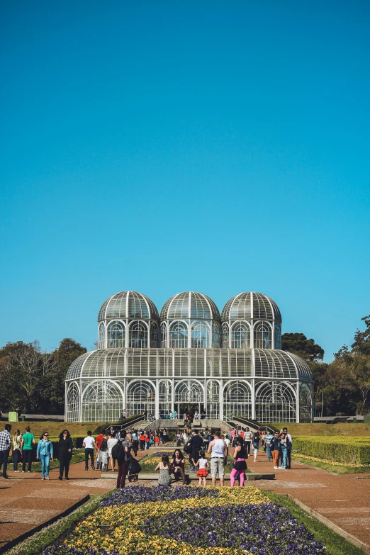 a group of people standing around a flower garden, by Christo, pexels contest winner, art nouveau, huge glass structure, são paulo, jerez, sunny day in a park