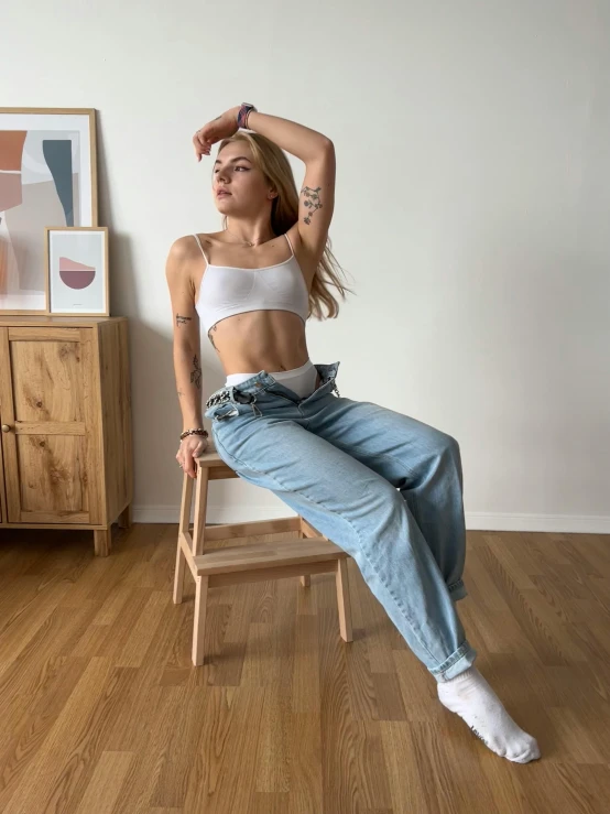 a woman sitting on top of a wooden chair, by Matija Jama, trending on pexels, hyperrealism, baggy jeans, wearing crop top, 90's photo, amouranth