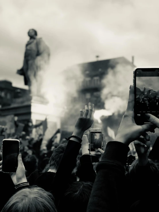 a crowd of people taking pictures of a statue, a black and white photo, by Matija Jama, pexels contest winner, happening, riot background, dystopian celebration, background image, pyrotechnics