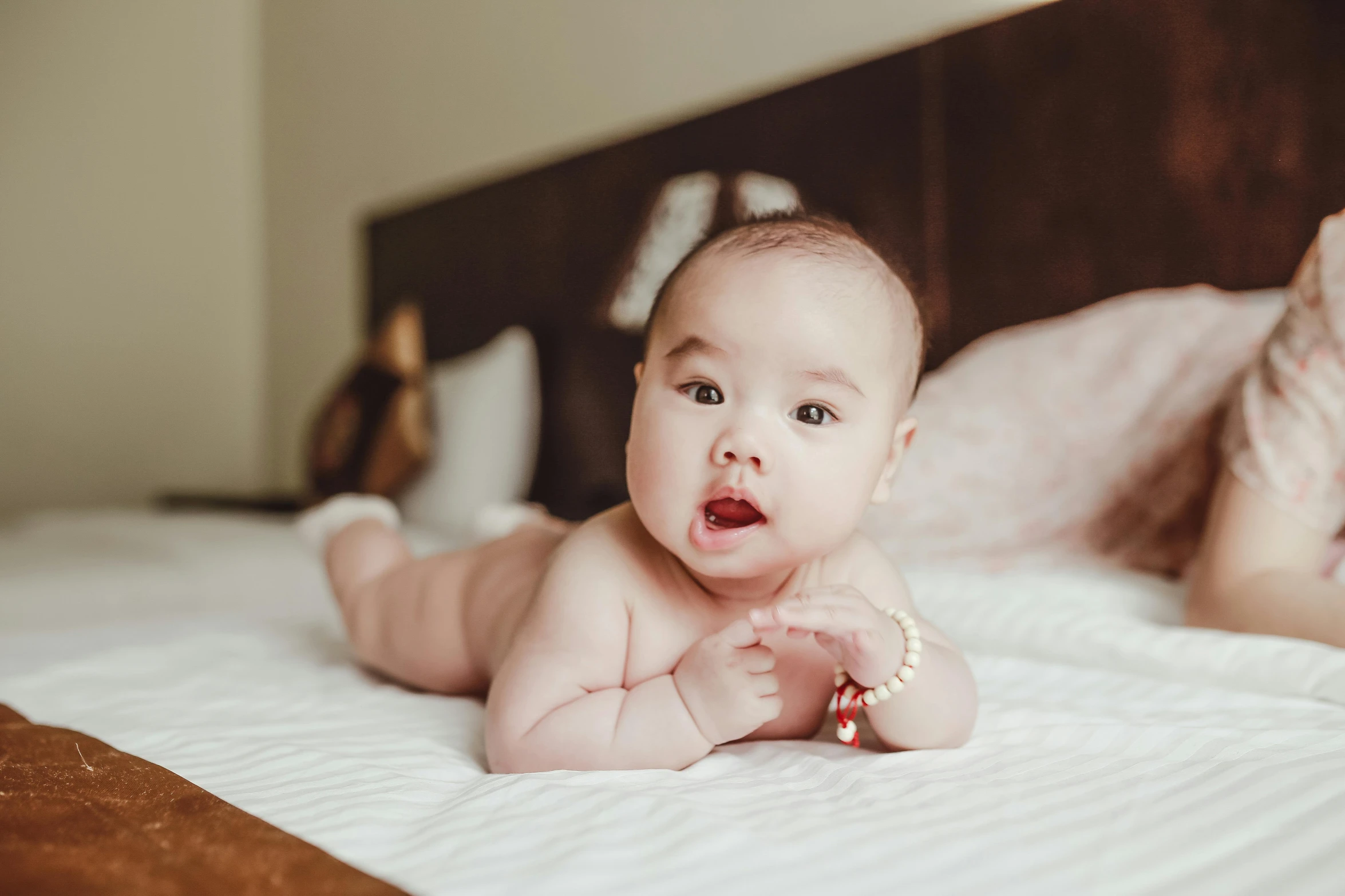 a baby laying on top of a bed next to a woman, pexels contest winner, happening, young cute wan asian face, bouncy belly, 1 5 0 4, ellie victoria gale