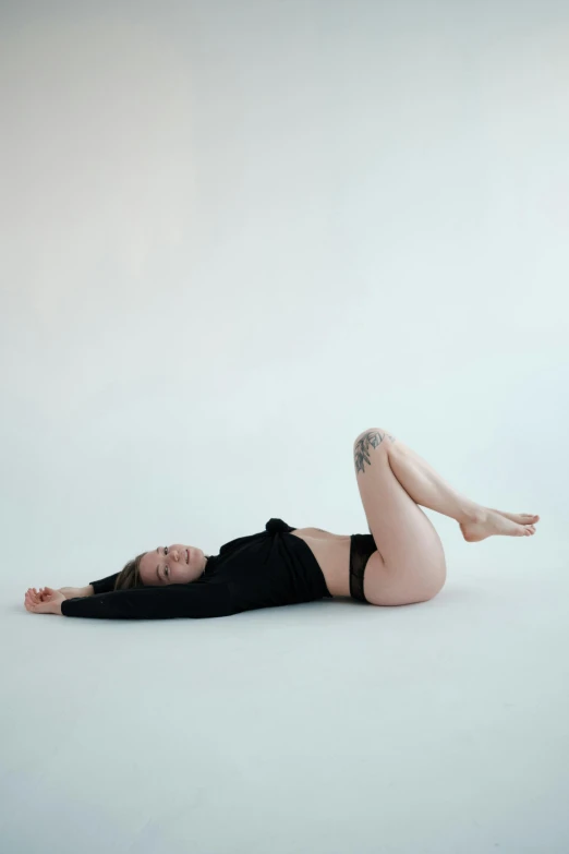 a woman that is laying down on the ground, inspired by Ren Hang, unsplash, minimalism, plain background, low quality photo, women full body, tattooed