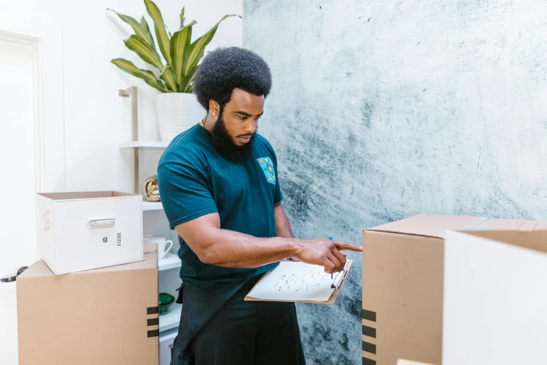 a man holding a clipboard in a room full of boxes, pexels contest winner, hurufiyya, a black man with long curly hair, profile image, maintenance photo, lachlan bailey