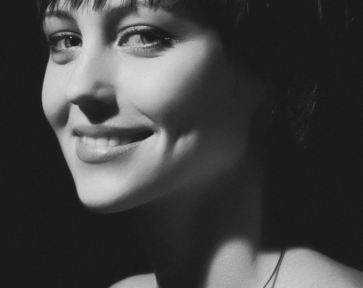 a black and white photo of a woman smiling, by Eugeniusz Zak, pixabay, fine art, with short hair with bangs, phoebe tonkin, taken in 1 9 9 7, pixie cut