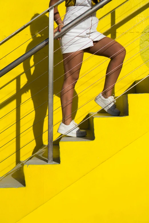 a woman is walking up a set of stairs, inspired by Alexander Rodchenko, trending on unsplash, colors: yellow, thighs, los angeles 2 0 1 5, sport