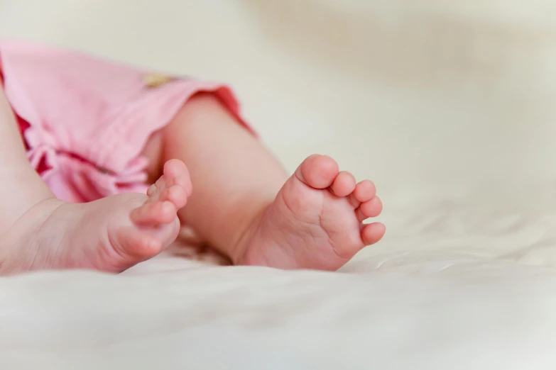 a close up of a baby's feet on a bed, by Ruth Simpson, pexels, pink, extra high resolution, laying down, modeled