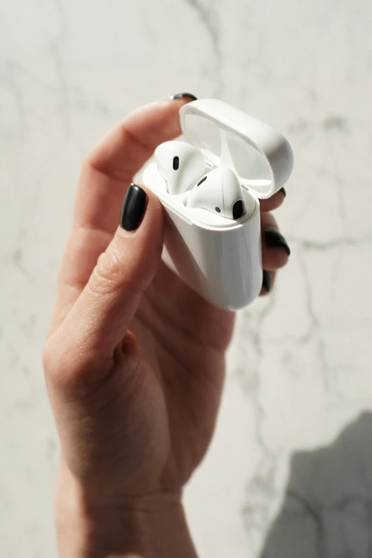 a person holding an airpods in their hand, inspired by Zaha Hadid, trending on pexels, glossy white metal, porcelain skin ”, top lid, retro style ”